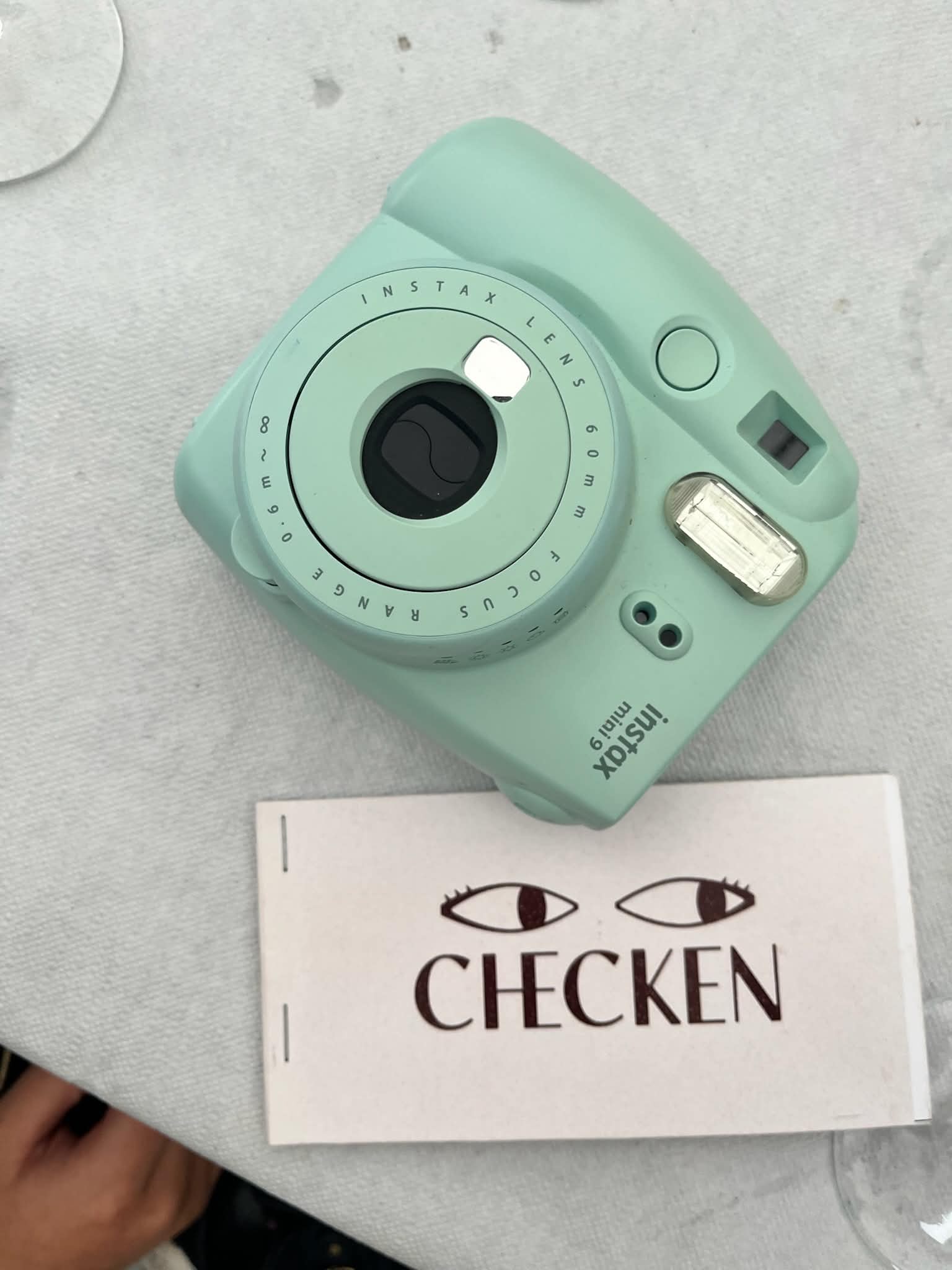 Checken flirtkort bredvid en mintgrön Instax-kamera